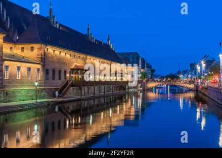 Blick auf den Sonnenuntergang über der Uferpromenade eines Kanals, der das Gebäude ancienne douanne in Straßburg, Frankreich, passiert Stockfoto
