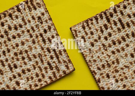 Eine Nahaufnahme von zwei Matzahs - Brot für das jüdische Passah, auf gelbem Hintergrund Stockfoto