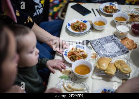 Abendessen mit einer lokalen uigurischen Familie in der Stadt Karakol im kirgisischen Issyk Kol Gebiet. Stockfoto