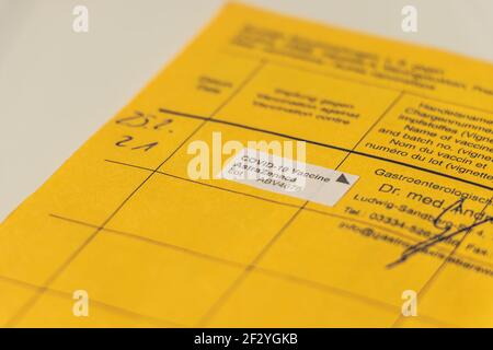 Gelbe Impfkarte mit Nachweis der Corona-Impfung. Eröffnetes Impfzertifikat der Weltgesundheitsorganisation mit dem Impfzertifikat Stockfoto