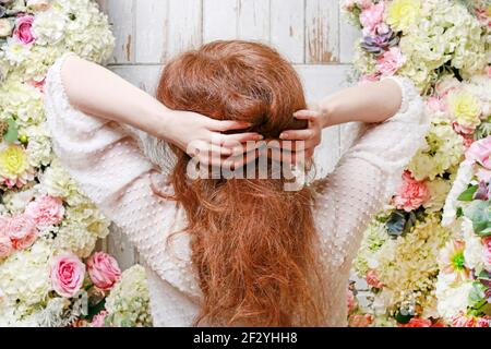 Frau steht vor der Tür mit romantischem Blumenschmuck mit Rosen-, Dahlia-, Hortensien- und Nelkenblumen. Stockfoto