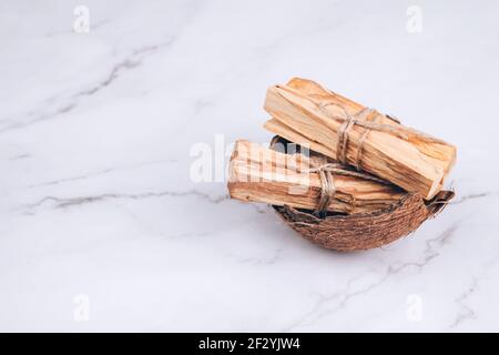 Palo Santo-Baum steckt in der Kokosnussschale auf Marmorboden - heiliger Weihrauchbaum aus Lateinamerika. Meditation, geistige Gesundheit und persönlich Stockfoto