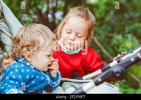 Schwester spielt mit ihrem Bruder im Kinderwagen, rollt das Baby die Straße hinunter Stockfoto