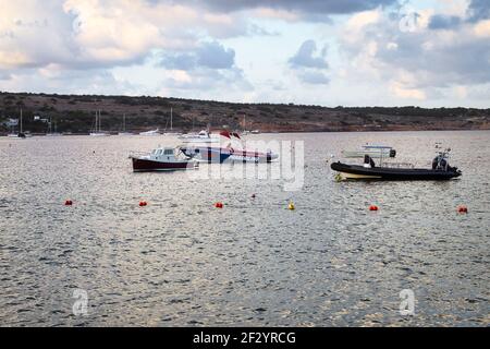 Boote ankerten im Wasser vor der Küste von Mellieha, Malta an einem Herbstabend. Stockfoto
