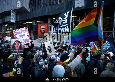 Demonstranten marschierten während der Demonstration mit Plakaten und Fahnen.beim einjährigen Jahrestag der Schüsse von Breonna Taylor in ihrer Residenz versammelten sich Demonstranten am Times Square. Taylor, ein Techniker in der Notaufnahme, wurde am 13. März 2020 während einer verpfuschten Polizeirazzia getötet, bei der die Polizei behauptet, dass Taylors' Freund den ersten Schuss abgefeuert habe, nachdem die Beamten sich selbst angekündigt hatten und einen Offizier verwundeten. Sechs Monate nach dem Drogenrazzia wurde der Familie Taylor 12 Millionen Dollar als unrechtmäßige Tötungsvereinbarung mit der Stadt Louisville Kentucky zugesprochen, die festlegt, dass die folgenden Änderungen in Th Stockfoto