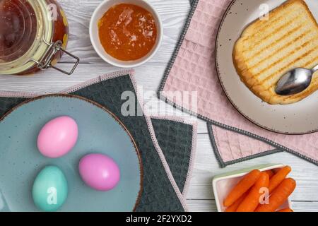 Farbiges Osterei auf dem Frühstückstisch mit Marmelade und geröstetem Brot. Stockfoto