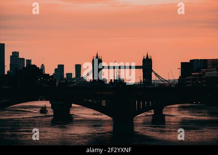 London UK Februar 2021 Spätnachmittag Winter Sonnenuntergang über der Themse, Umriss der Tower Bridge im Hintergrund. Doppeldeckerbusse crossin Stockfoto