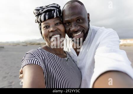 Glückliches afrikanisches Paar, das Selfie am Strand mit Handy macht Smartphone-Kamera während der Sommerferien - Liebe Beziehung Konzept Stockfoto