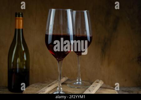 Zwei Gläser Rotwein. Die Flasche Wein steht auf dem Tisch. Weinhintergrund. Stillleben. Alkoholisches Getränk in einem Glas. Holzhintergrund. Stockfoto