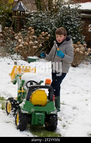 Ein achtjähriger Junge, der im Schnee spielt Stockfoto