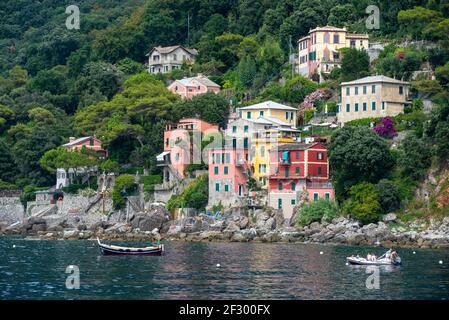 Farbige Häuser und Villen an der Küste bei Porto Pidocchio. Holzboot und ein Schlauchboot Stockfoto