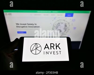 Person, die Mobiltelefon mit Firmenlogo des US-Vermögensverwalters ARK Investment Management LLC auf dem Bildschirm vor der Webseite hält. Konzentrieren Sie sich auf die Telefonanzeige. Stockfoto
