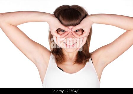 Junge Frau macht Brille mit Fingern. Das Mädchen sieht in improvisierten Brille, Handgesten. Isoliert auf weißem Hintergrund. Stockfoto