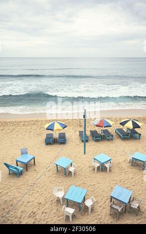 Luftaufnahme eines leeren tropischen Strandes mit Sonnenschirmen, Sonnenliegen, Tischen und Stühlen, Farbtonung angewendet, Sri Lanka. Stockfoto