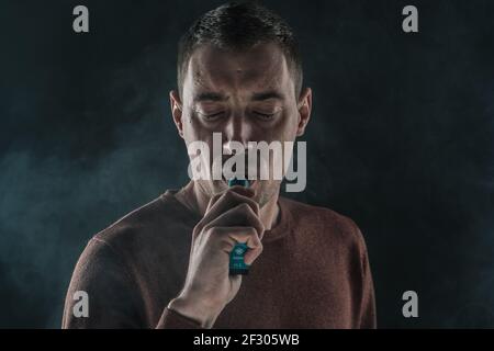 Hübscher Mann rauchend Vape auf schwarzem Hintergrund close-up Stockfoto