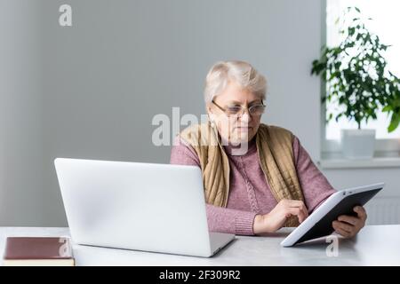 Serious reifen älteren erwachsenen Frau beobachten Training Webinar auf Laptop arbeiten von zu Hause oder im Büro. 60s Geschäftsfrau mittleren Alters, die Notizen während Stockfoto