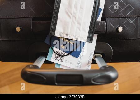 Reisekonzept nach Covid 19. Bordkarte der Fluggesellschaft, Schutzmaske und biometrischer Reisepass auf einer Gepäcktasche Stockfoto