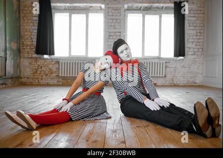 Männliche und weibliche Mime Künstler sitzen auf dem Boden Stockfoto