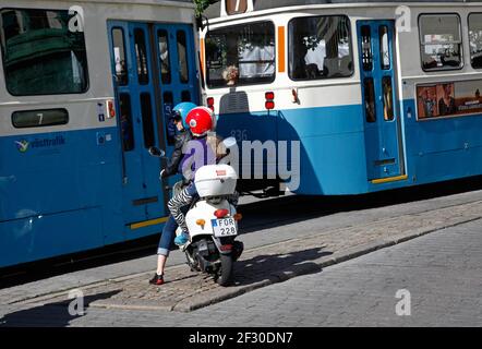 Vespa im Verkehr neben der Straßenbahn auf der Avenue in Göteborg. Stockfoto