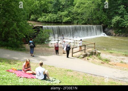 Menschen genießen einen sonnigen Tag am Blackwater Creek und Hollins Mill Dam & Wasserfall in Lynchburg, VA, USA Stockfoto