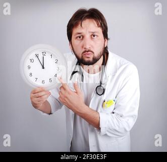 Der Arzt hält einen Wecker, der immer näher kommt Bis 12 Stockfoto