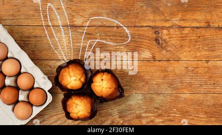 Hausgemachte Muffin mit bemalten Kaninchenohren. Muffin und Eier auf einem hölzernen Stockfoto