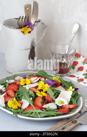 Erdbeer-Rucola-Salat mit Erdbeeren, Rocola, Parmesan und gehörntem Stiefmütterchen Stockfoto