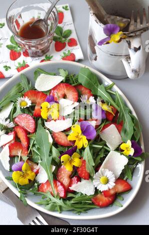 Erdbeer-Rucola-Salat mit Erdbeeren, Rocola, Parmesan und gehörntem Stiefmütterchen Stockfoto