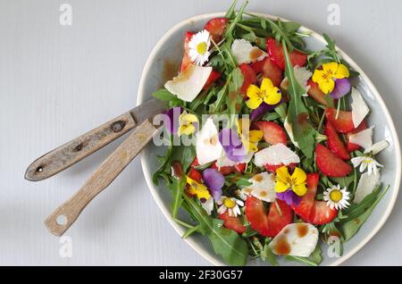 Erdbeer-Rucola-Salat mit Erdbeeren, Rocola, Parmesan und gehörntem Stiefmütterchen Stockfoto