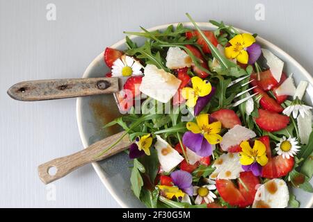 Erdbeer-Rucola-Salat mit Erdbeeren, Rocola, Parmesan und gehörntem Stiefmütterchen Stockfoto