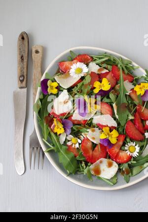 Erdbeer-Rucola-Salat mit Erdbeeren, Rocola, Parmesan und gehörntem Stiefmütterchen Stockfoto