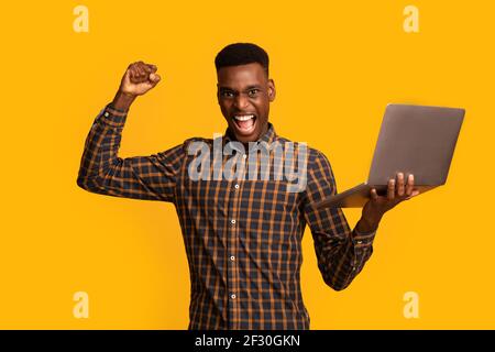 Euphoric Black Gguy Feiert Erfolg Mit Laptop, Raising Geballte Faust Stockfoto