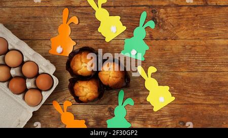 Hausgemachte Muffins mit Papierkaninchen. Muffin und Eier auf einem Holzhintergrund Stockfoto