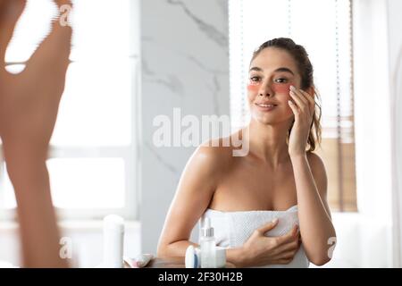 Frau Anwendung Unter-Auge-Patches Feuchtigkeitsspendende Haut Unter Den Augen Im Badezimmer Stockfoto