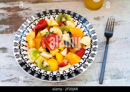 Natürlicher und gesunder Obstsalat mit Orange in einem Vintage-Teller, auf einer rustikalen Oberfläche. Gesunde Ernährung Konzept, Gesundes Leben. Blick auf den Zenith. Stockfoto