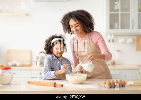 Glückliche schwarze Frau und Tochter machen Gebäck in der Küche Stockfoto