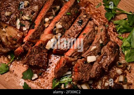 Frisch gebratenes, mittelseltenes Sirloin-Steak auf dem Schneidebrett, das in Butter, Knoblauch, Schalotte und Petersilie gebraten ist Stockfoto