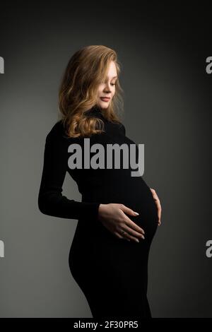 Schwangere Frau in schwarzem Kleid im Studio Stockfoto