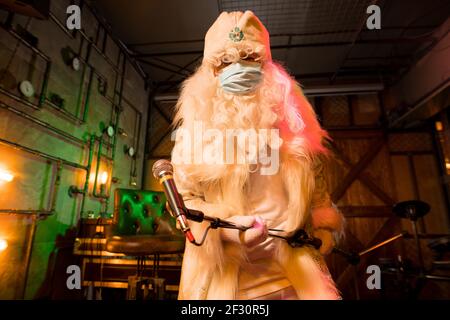 Ausdrucksstarker Weihnachtsmann-Gesang in Rockbar mit Maske Stockfoto