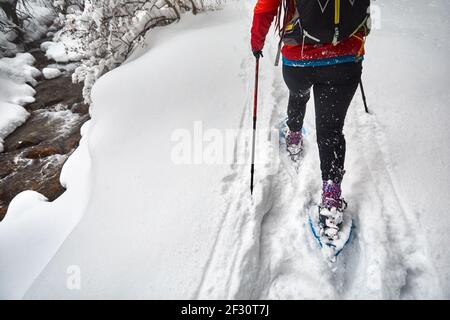 Frau mit Schauschuhen ist im Winter verschneiten Wald in der Nähe des Flusses in Almaty, Kasachstan zu Fuß Stockfoto