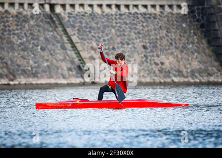 Prag, Tschechische republik - 12. März 2021. Junger Mann im roten Hemd segelt auf rotem Einkanu im Kanu-Sprint in Sonnenuntergang Stockfoto