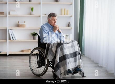 Einsamkeit behinderter älterer Menschen im Altersheim. Behinderter älterer Mann im Rollstuhl, der an Depressionen leidet Stockfoto