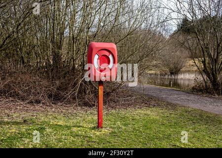 Rote Box auf einer Post Halten einer Rettungsgurt Auftriebshilfe An einem See in einem Wald in Derbyshire Stockfoto