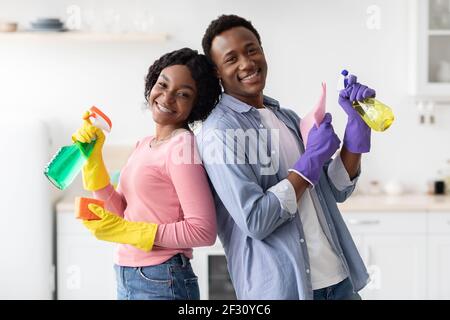 Positive afroamerikanische Mann und Frau mit Sprühflaschen Stockfoto