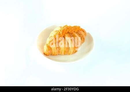 Frisch gebackene Butter gesalzenes Eigelb-Croissant auf weißem Teller. Croissant-Sandwich mit gesalzenem Ei, hausgemachtes Isolat mit weißem Hintergrund. Französische Vergangenheit Stockfoto