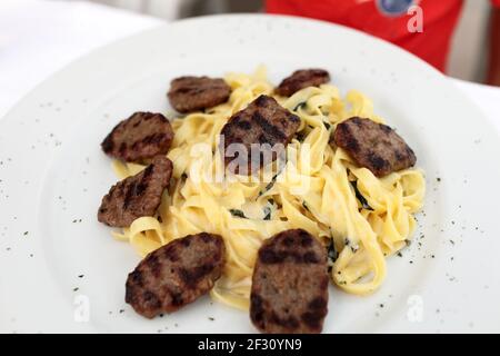 Koteletts mit Nudeln auf einem weißen Teller Stockfoto