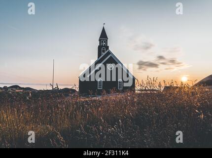 Alte hölzerne Zions-Kirche in der arktischen Stadt Ilulissat, mit Mitternachtssonnenlicht und blauem Himmel in Nordgrönland Stockfoto