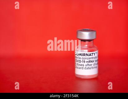 Teruel, Spanien - März 03 2021, Comirnaty, RNA-Impfstoff gegen Covid-19, entwickelt von Pfizer BioNTech auf rotem Hintergrund Stockfoto