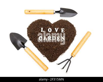 Kreative Anordnung der Garten Handwerkzeuge um ein Herz geformt Erdhaufen mit Schriftzug LOVE GARDEN aus Holz Zeichen auf weißem BA isoliert Stockfoto