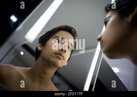 Teenager, der seine Haut im Spiegel überprüft Stockfoto